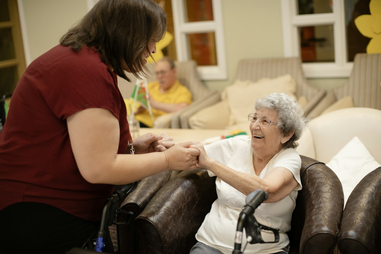 A caregiver holding hands with a smiling senior woman
