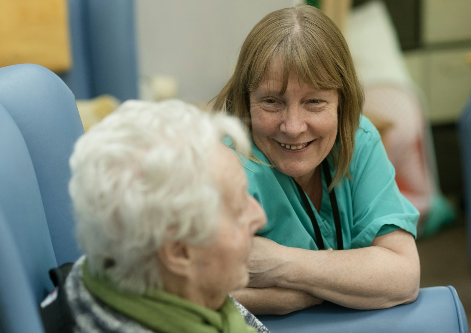 A smiling nurse leaning in to talk with a senior